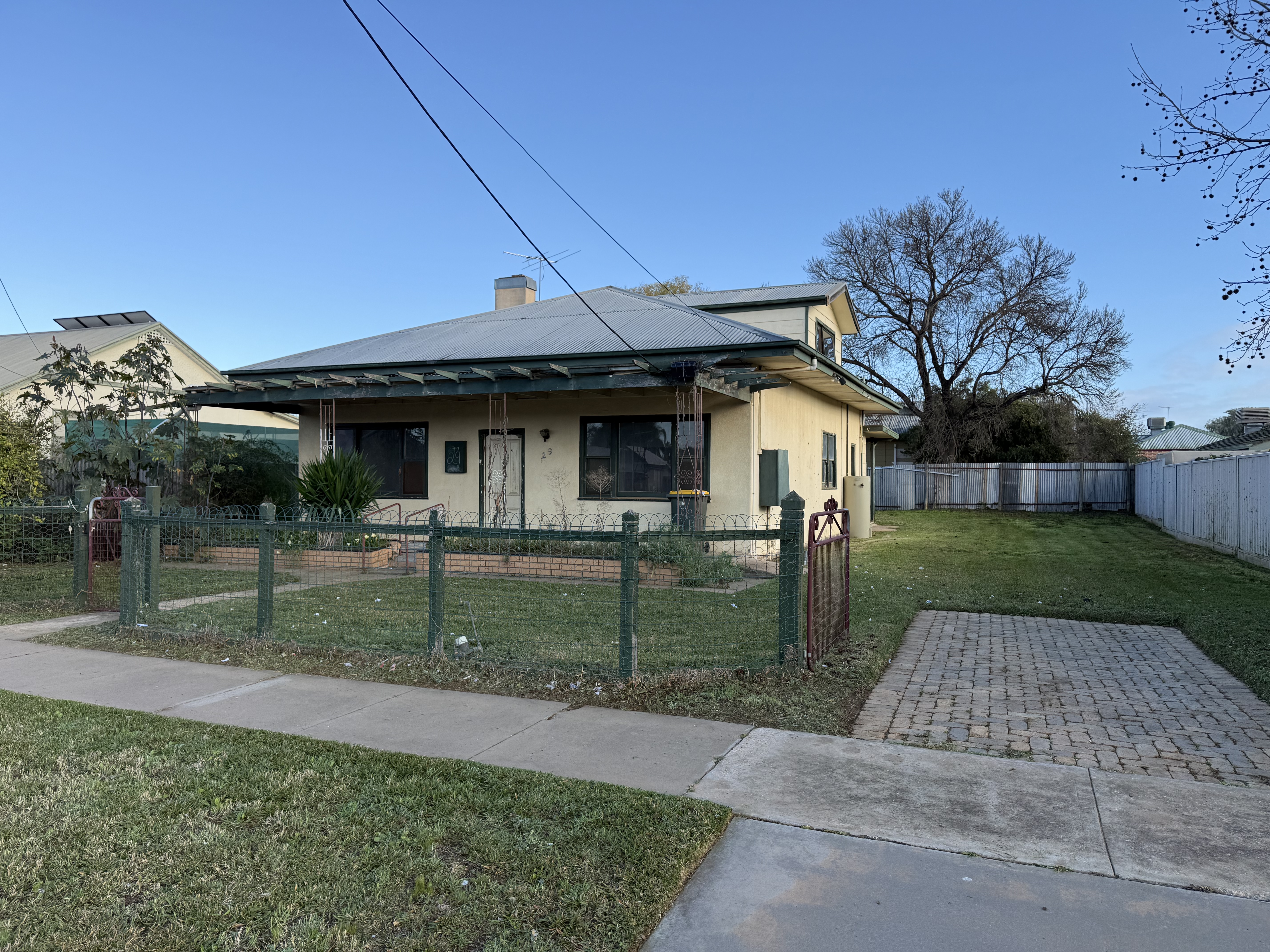 The property before renovation — rendered bungalow with original wire fencing and overgrown front garden